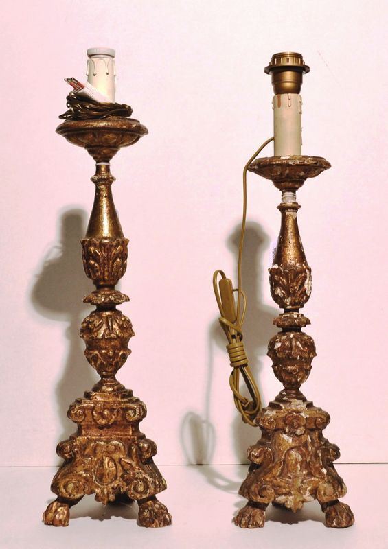 Due portaceri, in legno intagliato e dorato, fusto decorato a elementi      fogliacei, base tripode su piedi a zampa ferina, adattati ad elettricitÃ     alt. cm 59 e cm 58, danni (2)