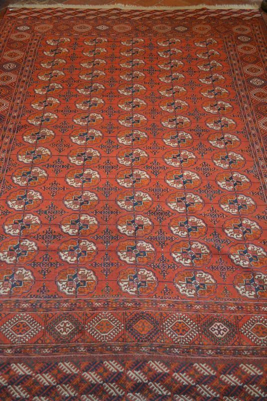 Tappeto bokara, fondo rosso con decori a rombi sagomati e motivi cruciformi nei toni dellavorio e del blu, cm 287x211