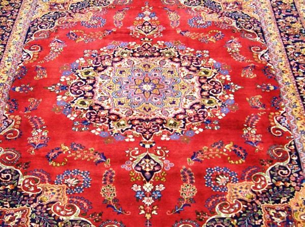 Tappeto persiano korassan, firmato, di vecchia manifattura, fondo rosso con medaglione centrale e bordura blu e rosso a motivo floreale, cm 395x295