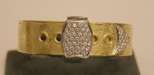 Bracciale rigido, in oro giallo e bianco bulinato, a forma di cintura, con pave' di brillanti, marcato Torrini, gr. 61