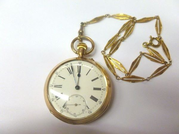 Orologio da tasca, fine sec. XIX, in oro 14 kt, con catena in oro a basso titolo                                                                      Cassa incisa  e cesellata con motivo a doppio scudo entro volute vegetali, corona di carica ad ore 12. Quadrante in smalto bianco con numeri romani    per le ore e numeri arabi per i minuti, secondi ad ore 6, lancette a foglia con finale piriforme. Movimento a carica manuale. Diam. mm 48. Corredato dia catena a maglie romboidali sagomate in oro a basso titolo
