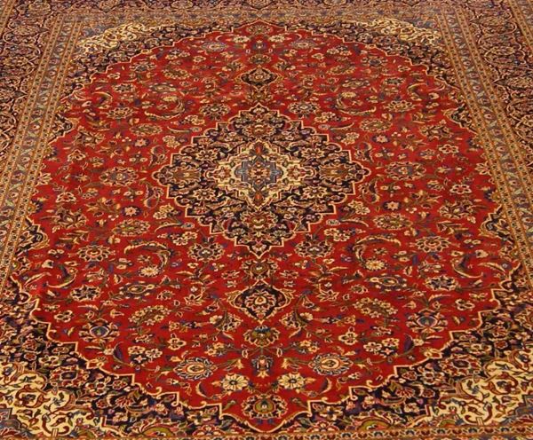 Tappeto persiano keishan, firmato, fondo rosso a motivo floreale con medaglione centrale e bordura blu, di vecchia manifattura, cm 400x300