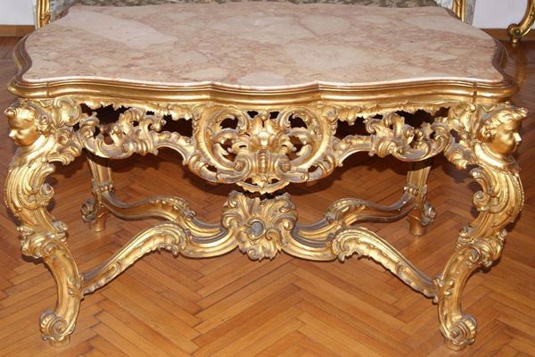 Tavolo, primi sec. XX, in legno intagliato con testine e dorato, piano in marmo, cm 128x80x77