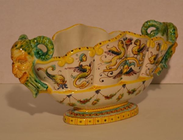 Coppa, sec. XX, di forma ovale in ceramica fondo bianco con decoro a figure ed animali fantastici in policromia, due anse modellate a teste di caprone, cm 37x13,5