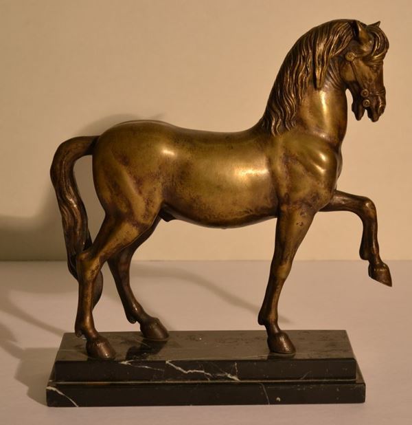 Scultura, sec. XX, in bronzo dorato raffigurante cavallo al passo su base   gradinata in marmo nero brecciato, alt. cm 32,5