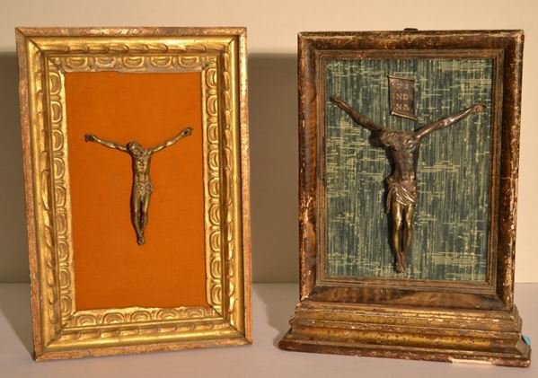 Crocefisso, sec. XIX, in argento modellato a tutto tondo con cartiglio      sovrastante, cm 21,5x18 applicato su pannello in velluto azzurro montato    entro cornice in legno dorato e laccato a finto marmo, cm 40x26,5 ed altro  crocefisso, sec. XIX, in bronzo dorato, cm 13,5x13, entro cornice di epoca  successiva (2)