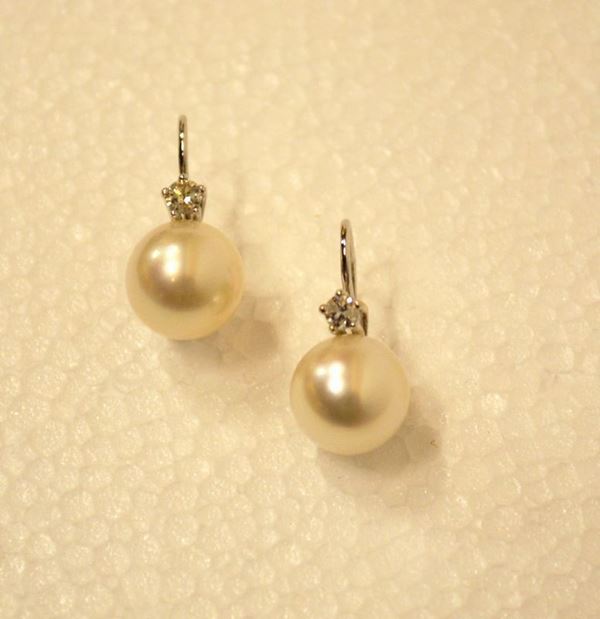 Paio di orecchini in oro bianco, perle e diamanti                           ciascuno realizzato con una monachella decorata da una perla di mm 12       sormontata da un brillante per complessivi ct 0,37                         (2)