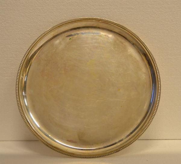 Vassoio di forma circolare in argento con tesa                            decorata da foglie lanceolate, diam. cm27, g 350