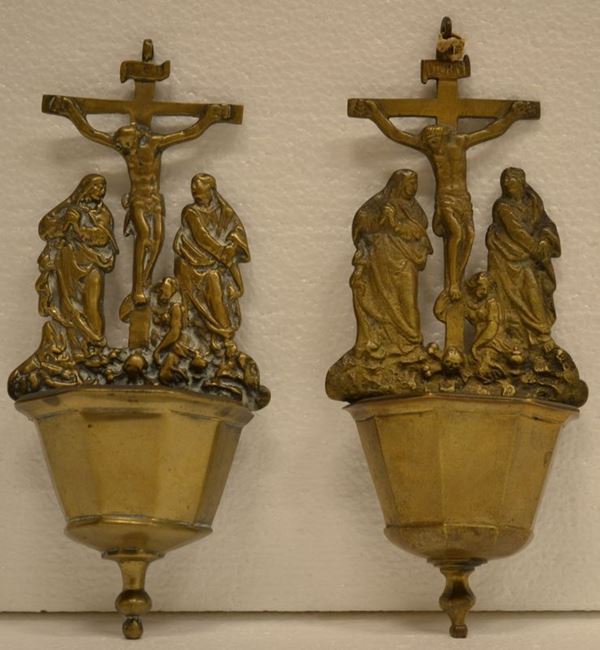 Coppia di piccole acquasantiere, in metallo dorato, vaschette sormontate da Crocefissione, alt. cm. 21 (2)