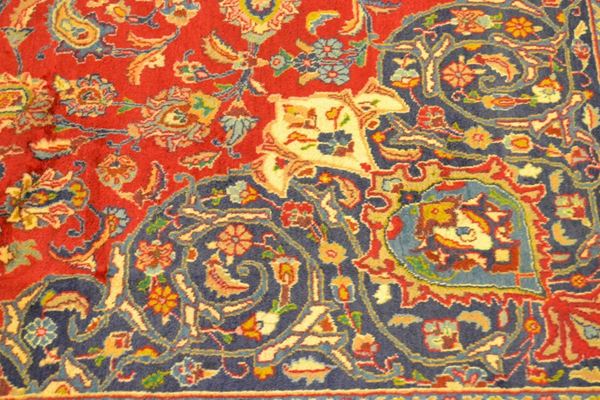 Tappeto persiano KORASSAN MASHAD FIRMATO, fondo rosso  a motivo floreale con medaglione centrale e bordatura blu, di vecchia manifattura, cm 380x297