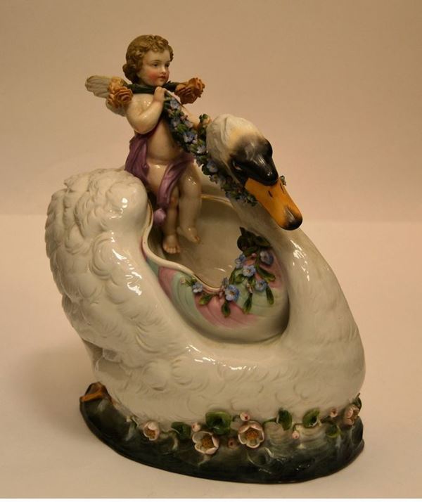 Scultura, secolo XX, in ceramica policroma raffigurante cigno con putto e fiori a rilievo, cm 31x30, difetti