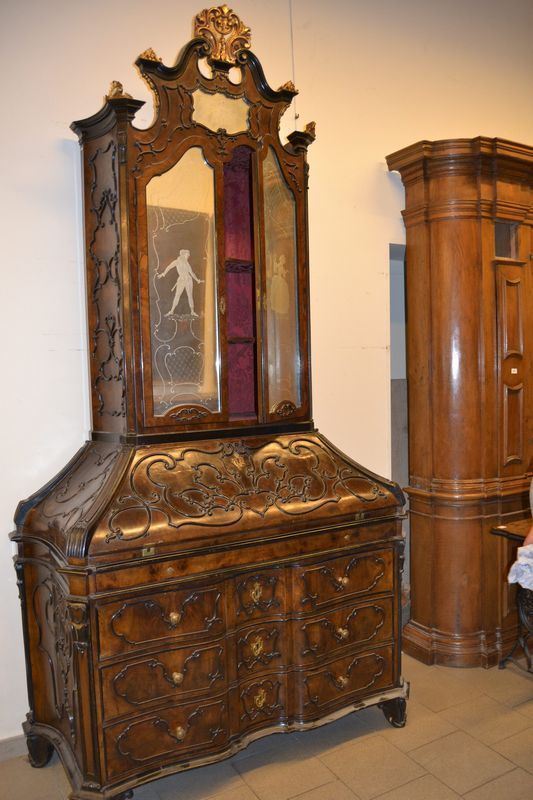 Troumeau, in stile XVIII, in noce intagliato e sagomato, a tre cassetti, tre sportelli due dei quali in vetro decorato, una ribalta con all'interno sportello e quattro cassetti