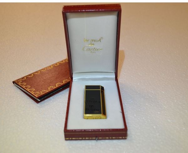 Accendino Le Must de Cartier, placcato in oro giallo                        e decorato in smalto nero, completo di astuccio originale