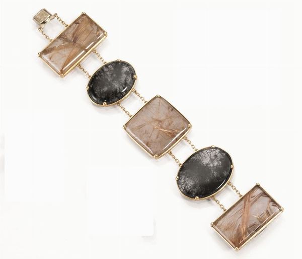 Bracciale in oro giallo e quarzi rutilati                                   realizzato con cinque quarzi rutilati di forma rettangolare, quadrata e     ovale montati in oro giallo e uniti fra loro da due fili di catena a maglia sottile, un quarzo danneggiato