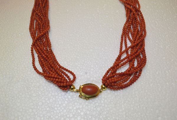 Collana in corallo e oro giallo                                             realizzata a undici fili di sferette in corallo rosso, fermatura ovale in   oro giallo centrata da un corallo cabochon, g 64