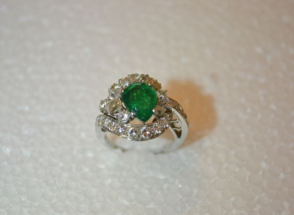 Anello in oro bianco, smeraldo e diamanti                                   al centro uno smeraldo a goccia di ct 1,50 circa montato entro una cornice  asimmetrica in brillanti per ct 2 circa, g 6