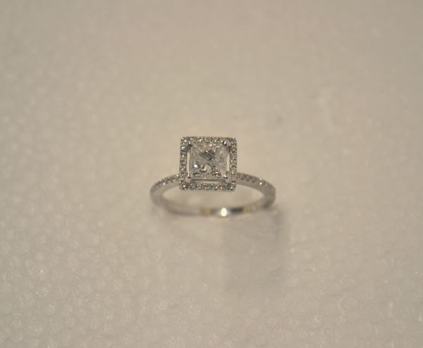 Anello in oro bianco e diamanti                                             al centro diamante di taglio princess di ct 1 circa montato entro una       cornice di piccoli brillanti, misura 13,5