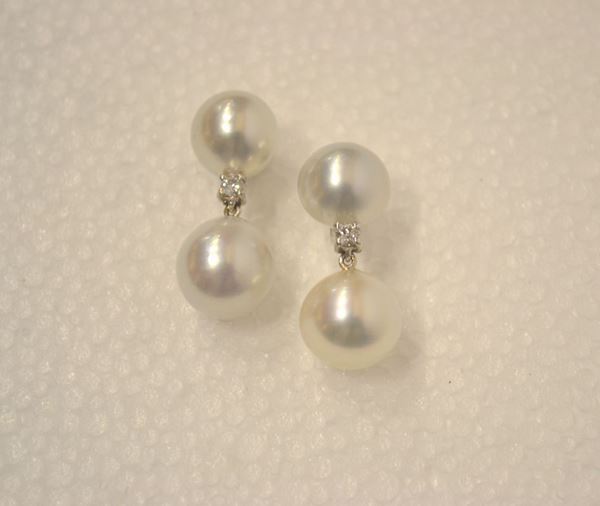 Paio di orecchini pendenti in oro bianco, perle South Sea e diamanti        ciascuno formato da una perla montata con un piccolo brillante a cui Ã¨      sospesa un'altra perla diam. mm 12                                         (2)