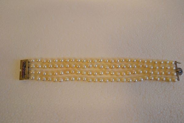 Bracciale in oro bianco, perle e rubini                                     realizzato a quattro fili di perle diam mm 10, fermatura rettangolare in    oro bianco satinato                                                         decorata da una linea di rubini