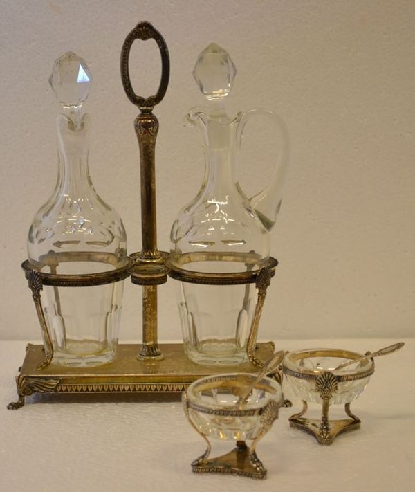 Oliera, sec. XX, in argento di gusto Impero, g completa di ampolle in       vetro, g 465 e due saliere en suite (3)