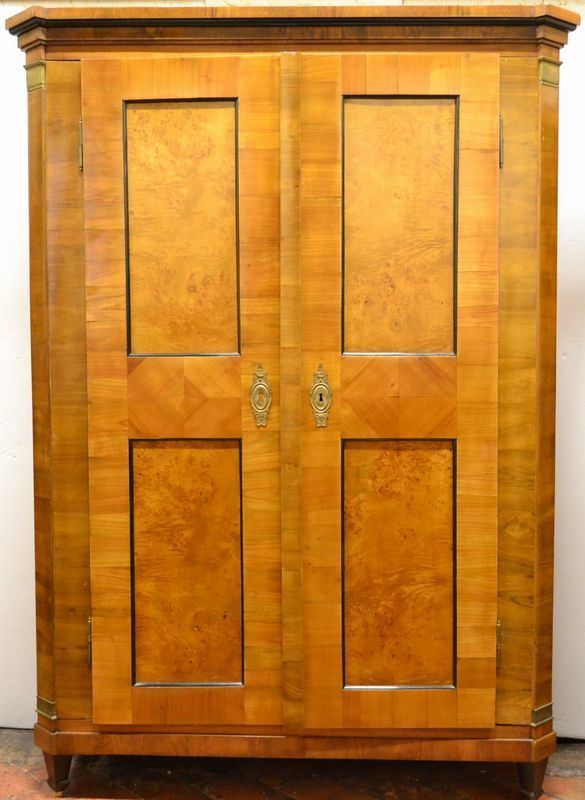 Piccolo armadio, Austria, fine sec. XIX, in ciliegio, noce e radica,        cappello modanato con angoli scantonati, due sportelli inquadrati da lesene stilizzate con basi e capitelli in bronzo, gambe troncopiramidali           ebanizzate, interno con piani regolabili, cm 136x47x201