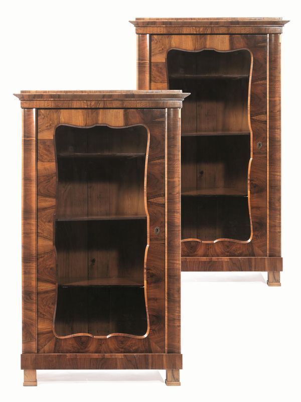 Coppia di piccole librerie da studio, Austria, periodo Biedermeier, fine    sec. XIX, in radica di noce, fronte ad uno sportello a vetri con luce       sagomata inquadrato da lesene stilizzate, base rettilinea, piedi a plinto,  cm 109x63x182 (2)