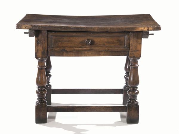 Piccolo tavolo, Emilia, sec. XVII, in noce a patina scura, piano            rettangolare, un cassetto nella fascia, gambe tornite a balaustro, riunite  da traverse, piedi a dado, cm 113x73x82, alcuni restauri