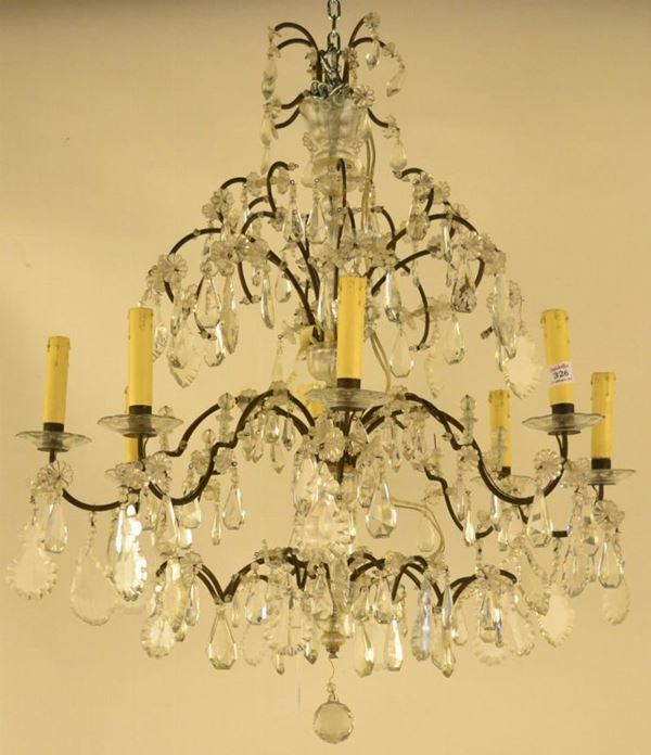 Lumiera, sec. XIX, in ferro battuto a otto bracci ricurvi, con pendenti in  vetro tagliato, diam. cm 70 circa