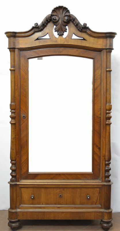 Armadio, fine secolo XIX, in noce intagliato, cappello con motivo           fogliaceo, fronte con anta a specchio e cassetto sottostante, cm 121x60x255