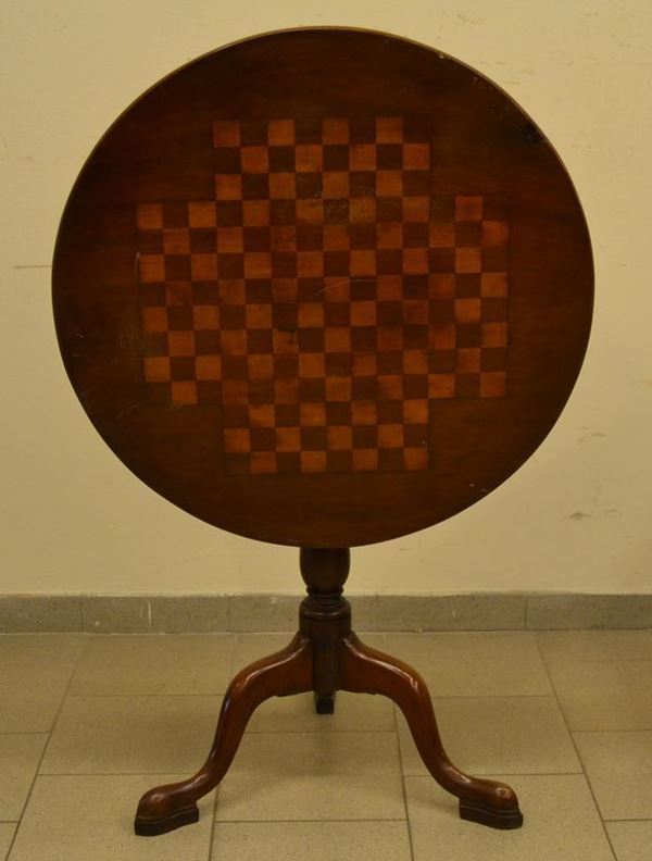 Tavolino, inizi sec. XX, in noce, con piano a vela decorata a scacchiera, gambe tornite su tre piedini sagomati, cm 76x77