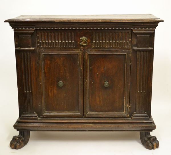 Credenzino in stile Seicento, in noce a patina scura, fronte a due          sportelli e due cassetti, piedi a zampa ferina, cm 95x35,5x83, danni