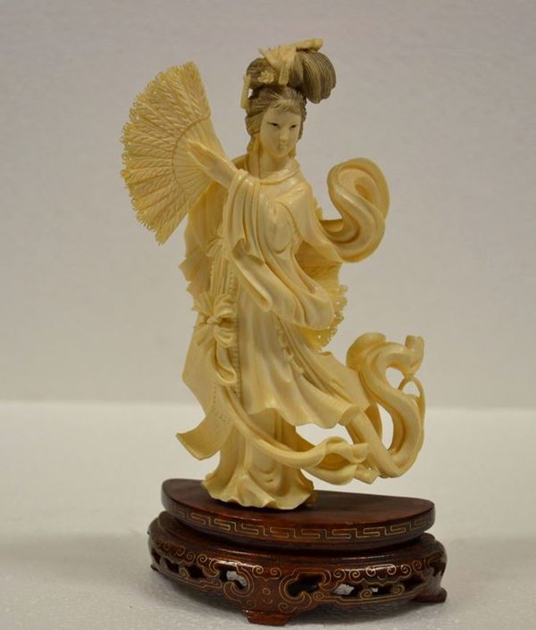 Scultura Cina sec. XX, in avorio raffigurante figura femminile dalle vesti  svolazzanti alt. cm 16,5 su base in legno alt. cm 4