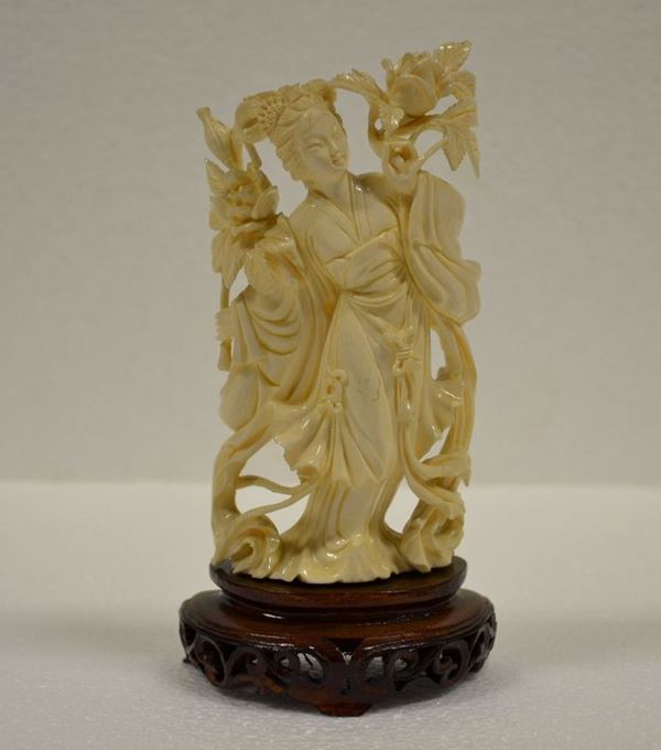 Scultura in avorio Cina sec. XX, raffigurante figura femminile con fiori di loto, alt. cm 16 su base in legno alt. cm 3,5