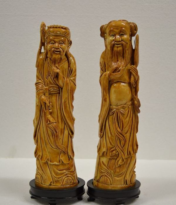 Coppia di sculture Cina sec. XX, in avorio raffiguranti saggi stanti alt.   cm 25 su base in legno alt. cm 2,5 (2)