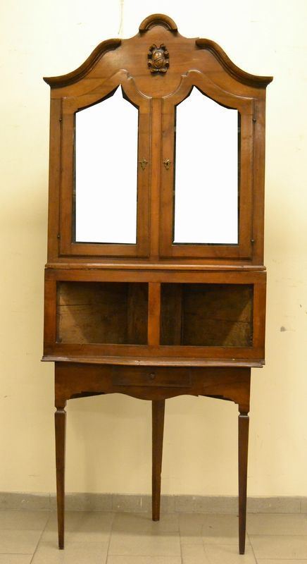 Angoliera, sec. XIX, in noce, a due corpi, due sportelli con vetri, un cassetto e vani a giorno, cm 92,5x48x222