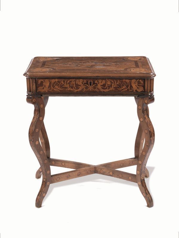 Tavolino da lavoro, sec. XIX, in noce intarsiato, piano rettangolare        decorato da mascheroni angolari e composizione floreale al centro, fascia   con girali vegetali e puttini, un cassetto, gambe sinuose riunite da        crocera, cm 66x47x73