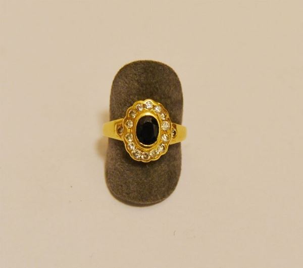 Anello in oro giallo con zaffiro ovale, contornato di brillanti, g 5