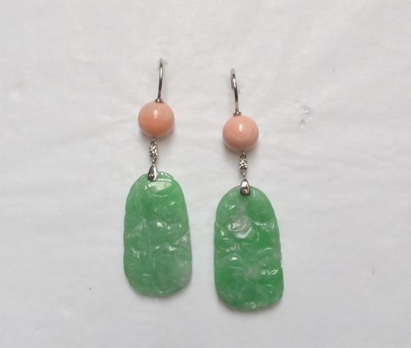 Paio di orecchini pendenti in oro bianco, giada, corallo e diamanti ciascuno formato da una sferetta in corallo peau dâ€™ange a cui Ã¨ sospeso, tramite un piccolissimo brillante un elemento sagomato in giada intagliata a motivi vegetali