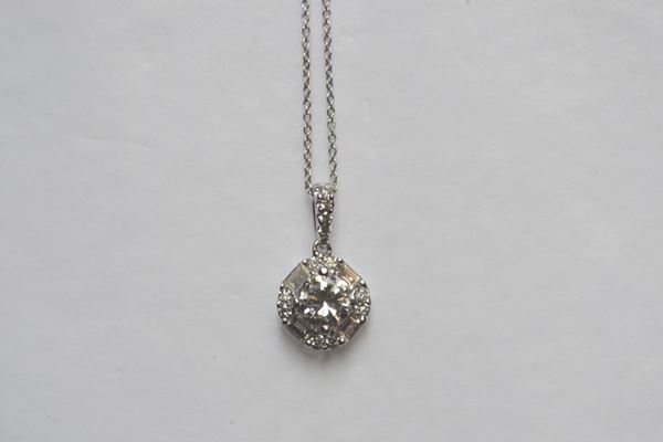 Pendente punto luce in oro bianco e diamanti realizzato con un brillante di ct 0,32 montato entro una cornice di diamanti taglio baguette e brillante per ct 0,46, corredato di catena in oro bianco a maglia sottile