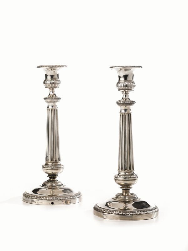 Coppia di candelieri, Milano, sec. XIX, in argento, fusto scanalato con     profili cesellati a palmette, basi circolari con bordo sbalzato ad ovoli e  con foro per l'applicazione elettrica, alt. cm 25, g 500 (2)