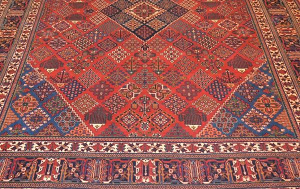 Tappeto persiano, fondo rosso con decoro a rombi e motivi geometrici multicolor, bordura rossa e avorio, cm 305x259
