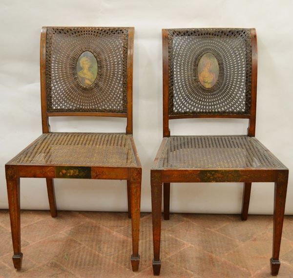 Coppia di sedie, Inghilterra, sec. XIX, in satin wood dipinte a motivi floreali, spalliera lievemente arcuata centrata da medaglione ovale dipinto  con  dama vestita, gambe anteriori troncopiramidali e posteriori a sciabola, sedile in cannettÃ¨ danni alla pittura (2)