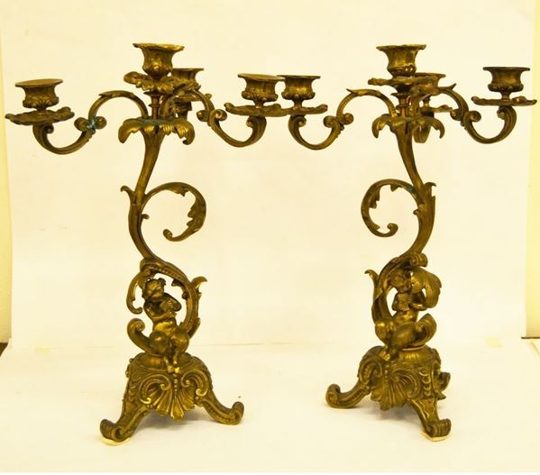 Coppia di candelieri, Francia, sec. XX, in bronzo lavorato a cinque luci, putti centrali, base poggiante su tre piedini sagomati, cm 28x40