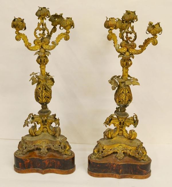 Due portacandele da terra, sec. XIX, in bronzo, con fusto centrale sagomato a motivi vegetali, finali a cinque fuochi a forma di foglie, base in legno, alt. cm 44