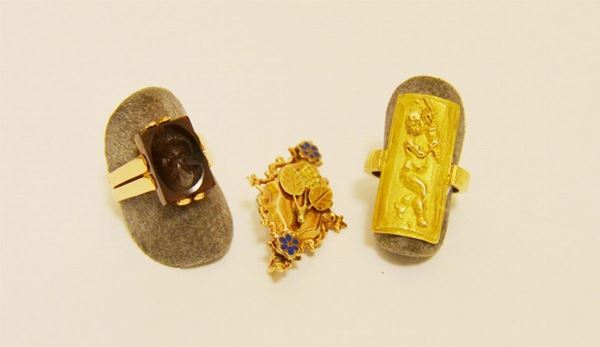 Lotto composto da: spilla in oro giallo, anello in oro giallo con scudo e putto in altorilievo, e anello in oro giallo con corniola incisa, tot. g 17,5 ( 3 )