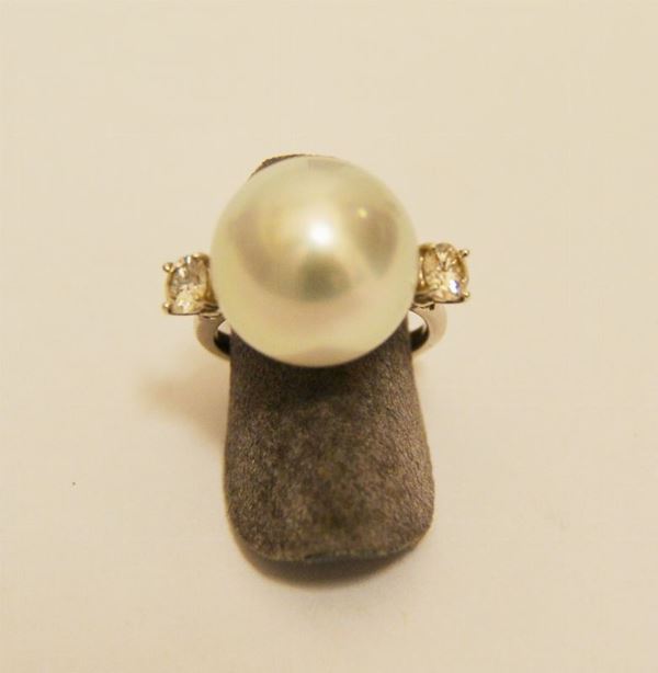 Anello in oro bianco, con perla centrale diam. mm 15 e due brillanti laterali