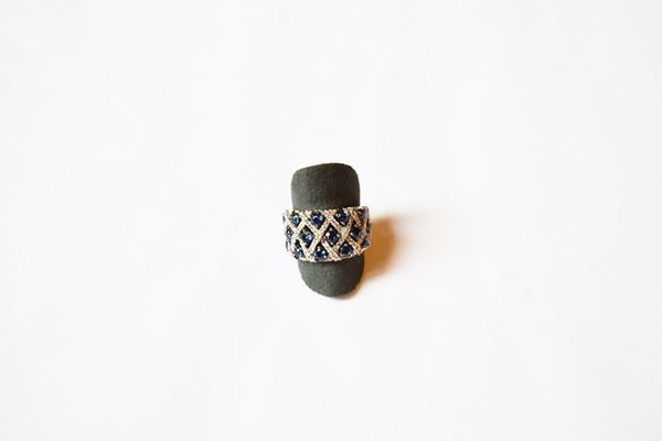 Anello in oro bianco, diamanti e zaffiri, realizzato come una fascia traforata con un motivo ad intreccio in brillanti per ct 0,70 e zaffiri per ct 1,40 circa, g 8, misura 14