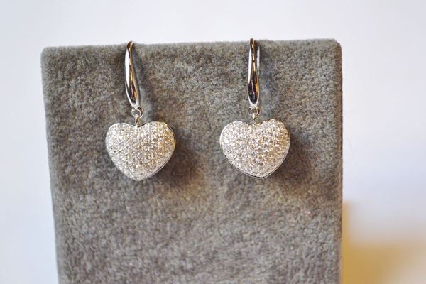 Paio di orecchini pendenti in oro bianco e diamanti, ciascuno realizzato con una monachella a cui Ã¨ sospeso un cuore decorato in pavÃ© di brillanti per ct 0,80 circa, g 4