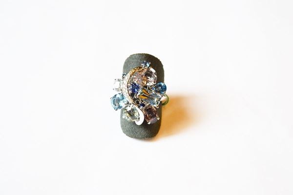 Anello in oro bianco, acquemarine, zaffiri e diamanti, la parte anteriore realizzata come una voluta floreale stilizzata formata da acquemarine, zaffiri e brillanti di tagli vari montati a griffe. Zaffiri per ct 3,90, acquemarine per ct. 3 circa, g 8, misura 13