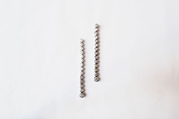 Paio di orecchini pendenti in oro bianco e diamanti, ciascuno formato da una linea di quattordici brillanti montati entro castoni circolari per complessivi ct 2, 40 circa, g 8